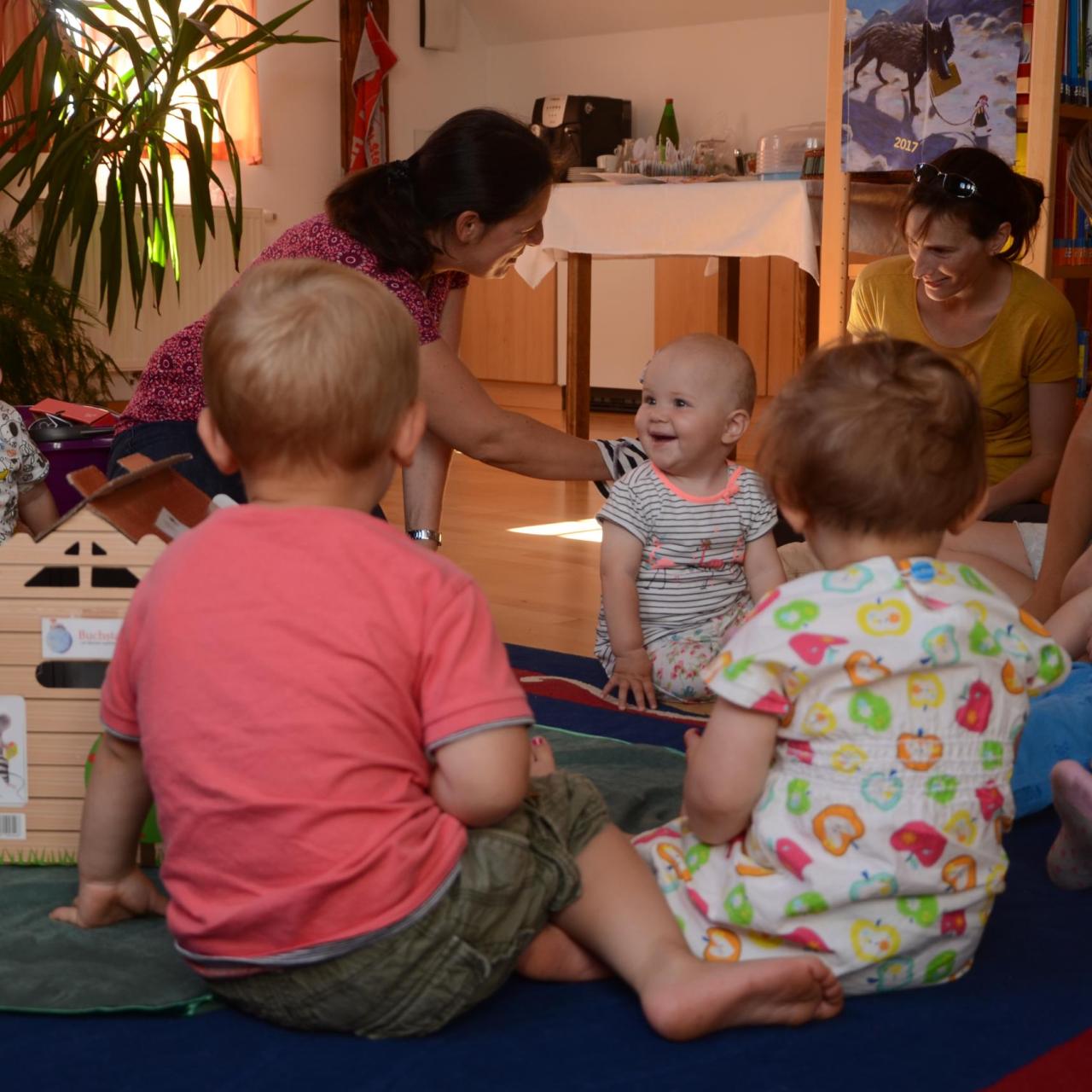 Kinder sitzen am Boden und hören gespannt zu.